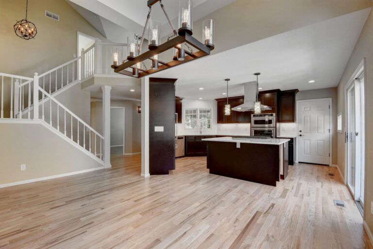 Large remodeled Denver kitchen with dark wood cabinets, quartz countertops, and a large center island and pendant lighting overhead.