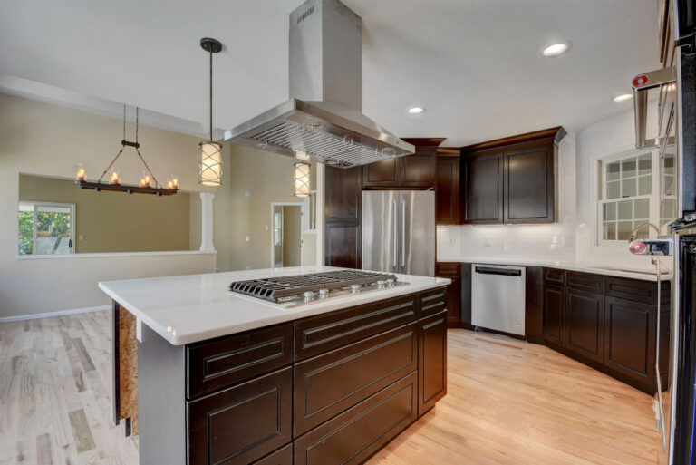 Large remodeled Denver kitchen with dark wood cabinets, quartz countertops, and a large center island and pendant lighting overhead.