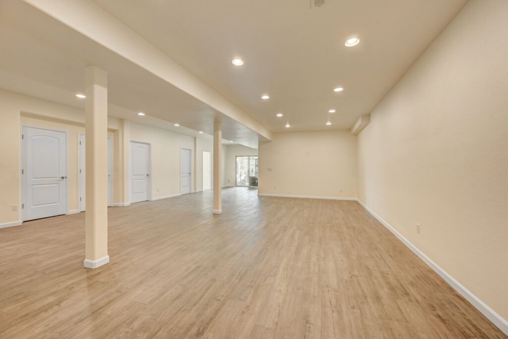 Full finished remodeled Denver basement with light hardwood floors, cream walls, white baseboards and trim, and recessed lighting.