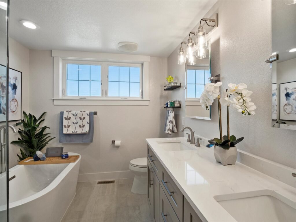 Updated bathroom with gray cabinets and white quartz countertops and modern standalone tub.